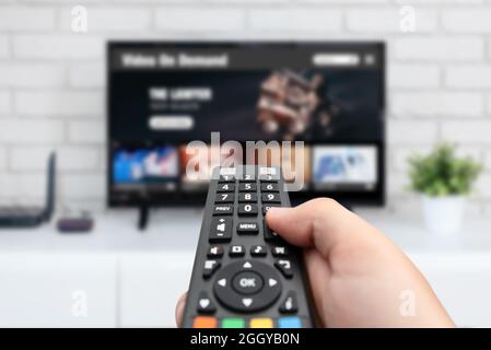 Man watching TV, remote control in hand. VOD service on TV Stock Photo
