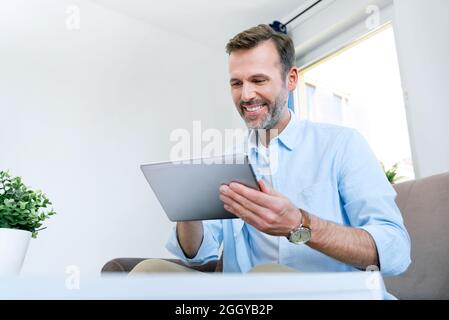 Handsome businessman working from home. Using app on tablet to telecommuting or sales reporting Stock Photo