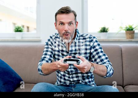 Man playing computer games, playing the console, holding pads in hands the. Joy of playing computer games Stock Photo