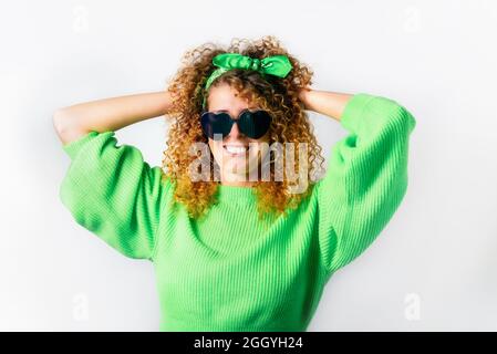 Portrait of happy smiling woman in a bright green pullover and heart-shaped sunglasses on white background. Love, Express emotions, positive facial Stock Photo