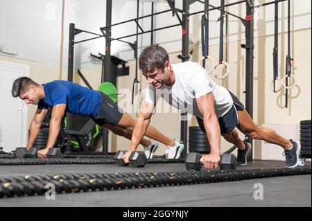 Two strong men doing push-ups in gym. High quality photo. Stock Photo