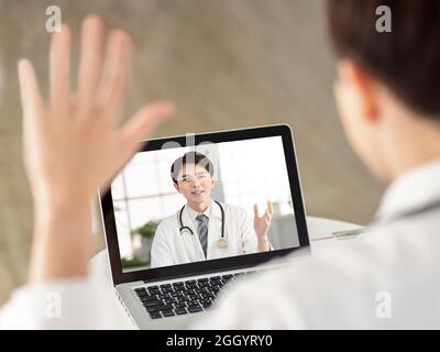 Back view of doctor making video call with his colleague. Stock Photo