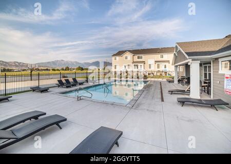 Community pool of a residential area with black lounge chairs and clubhouse Stock Photo