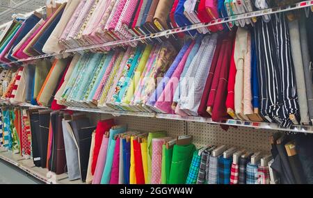 Different colors of cloth bolts on display for sale in a supermarket aisle. Stock Photo