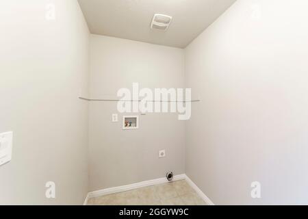 Tiled empty laundry room with hot and cold laundry connections Stock Photo