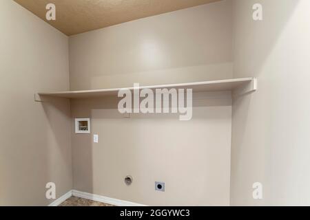 Empty laundry room interior with wall mounted shelf Stock Photo
