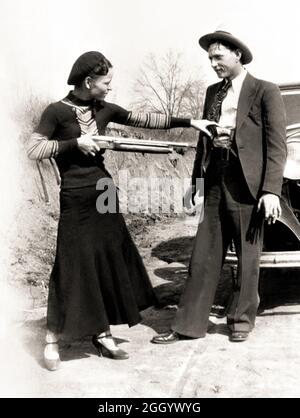 1934 , Arkansas , USA : The famous gangsterns  BONNIE PARKER  ( 1910 - 1934 ) and CLYDE BARROW ( 1909 - 1934 ). Contrary to popular belief the two never married. They were in a long standing relationship. Posing in front of a 1932 Ford V8 automobile where Bonnie and Clyde dead on May 23, 1934 . Unknown photographer . - OUTLAWS - KILLER - ASSASSINO - delinquente - criminalità organizzata  - GANGSTERN - Bos - CRONACA NERA - CRIMINALE - car - automobile - hat - cappello - fucile - arma - gun - rifle - shoes - scarpe ---  Archivio GBB Stock Photo