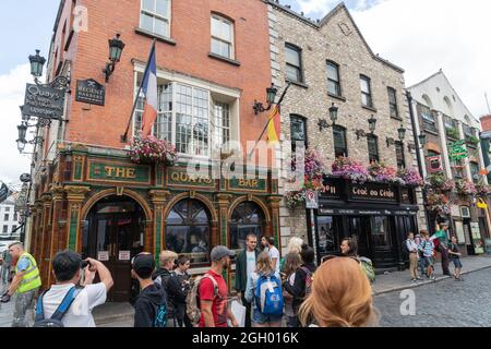 Dublin, IRELAND - AUGUST 10 2017; Young tourists in street outside well known Irish The Quays Bar in Temple Bar district of city Stock Photo