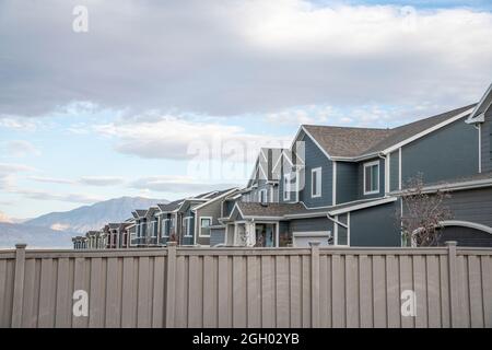 Row of two-storey houses in a residential area with beige vinyl fence at the front Stock Photo