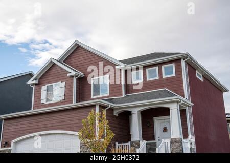 Low angle view of a two-storey house with brown vinyl wood and concrete sidings Stock Photo