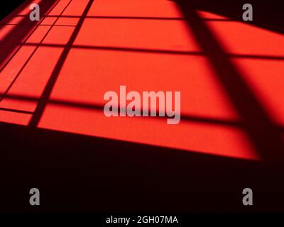 Red carpet with abstract lines on surface, sunlight on red rug, silhouettes and shadows on the floor Stock Photo