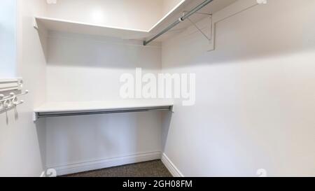 Pano Walk in closet of house with empty built in shelves and two levels ...