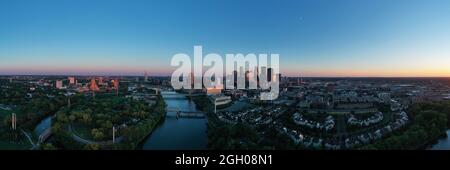 Sunset comes to the riverfront and downtown area of the northern city of Minneapolis MN in long panoramic Stock Photo