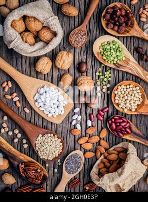 Various legumes and different kinds of nutshells in spoons. Walnuts kernels ,hazelnuts, almond ,brown pinto ,soy beans ,flax seeds ,chia ,chickpea ,re Stock Photo