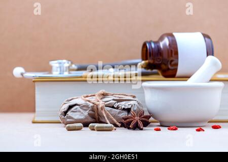 Alternative health care dried various Chinese herbs in the white mortar and herbs capsule on brown background. Shallow depth of field focus on star an Stock Photo