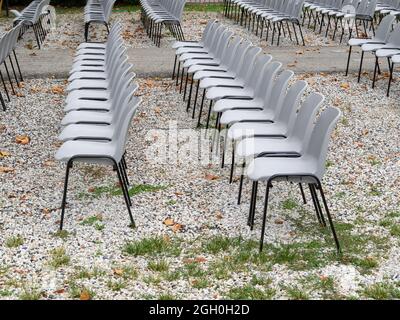 group of empty grey plastic chair arranged in rows waiting for the people after coronavirus covid 19 pandemic Stock Photo