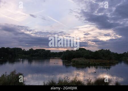 Evening sunset over a lake and trees at Lackford Lakes in Suffolk Stock Photo