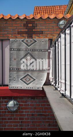a carpet on a red brick wall forms parallel and vertical lines,  Ronne, Denmark Stock Photo