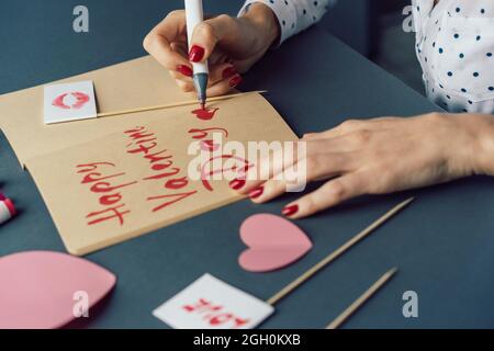 Woman writes in a sketch book with a felt-tip pen Happy Valentine's Day. Stock Photo