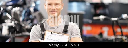 Handsome auto mechanic posing in car service and holding documents in hands Stock Photo