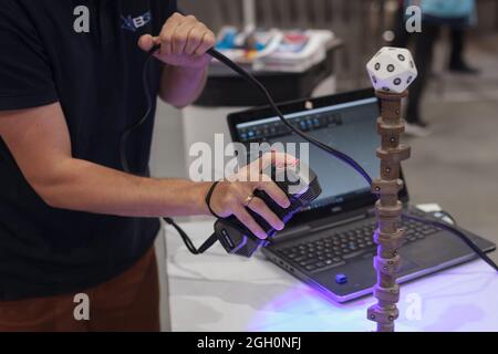 Poznan, Poland 01 Sep 2021:ITM Industry Europe, high-tech EXPO. Man Using Portable Laser Scanner to Import 3D CAD Model. Reverse engineering. Stock Photo