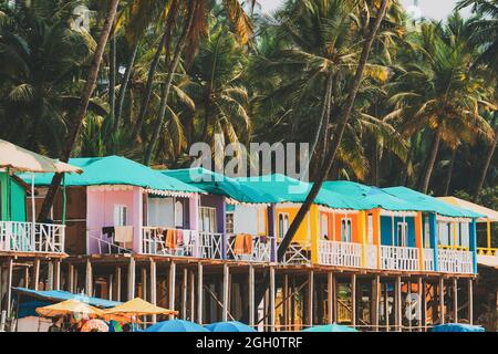 Canacona, Goa, India. Famous Painted Guest Houses On Palolem Beach Against Background Of Tall Palm Trees In Sunny Day.