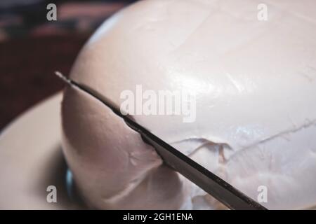 Mozzarella Bufala close up while cutting with a knife Stock Photo