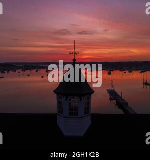 Building with compass on roof in front of beautiful lake against the red sky at sunset Stock Photo