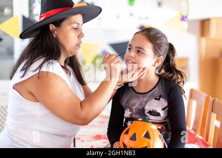 Mother doing her daughter's makeup for Halloween party. Stock Photo