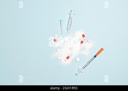 Top view medical composition of syringe with medication, antibiotic vial, pills on blue background. Healthy lifestyle concept. Stock Photo
