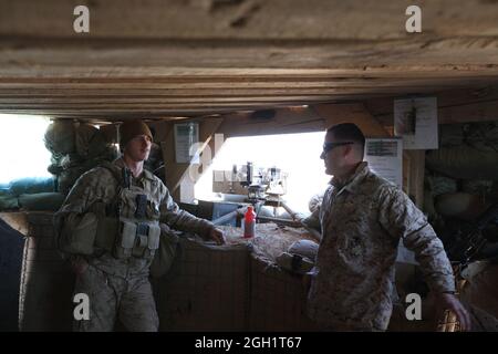 Navy Lt. Eric Hammen, right, talks to Lance Cpl. Steven Cox, an ammunition technician with 'The Magnificent Bastards,' 2nd Battalion, 4th Marine Regiment, at Forward Operating Base Edinburgh in Helmand province, Afghanistan, Jan. 1. Cox, a native of Pensacola, Fla., was about to begin guard duty in an observation post at the base. Hammen, a chaplain with 2nd Marine Aircraft Wing (Forward), and a native of Little Chute, Wis., visited Forward Operating Base Edinburgh on New Year's because the outpost doesn't have a chaplain of its own. Coalition forces in Afghanistan brought in the New Year by c Stock Photo