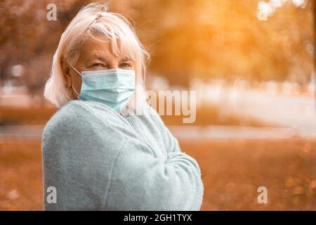 Coronavirus, COVID-19 Pandemic concept. Blonde woman in wearing face mask protective for disease virus SARS-CoV-2 at the city street Stock Photo