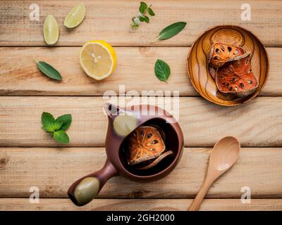 Herbal tea pot with fresh herbs sage ,peppermint ,dried indian bael, honey, lime and lemon on rustic wooden background. Stock Photo