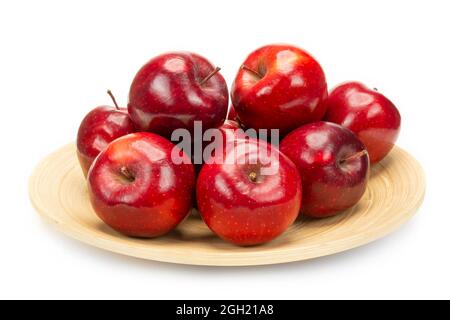 A bunch of fresh red apples on a bamboo plate, isolated on white background. Stock Photo