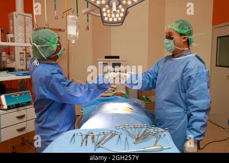 Two surgeons doctor shake hands with trust and confident give promise to work  for patient in operation room. Stock Photo