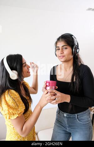 Young Indian girls with headphones having fun at home Stock Photo