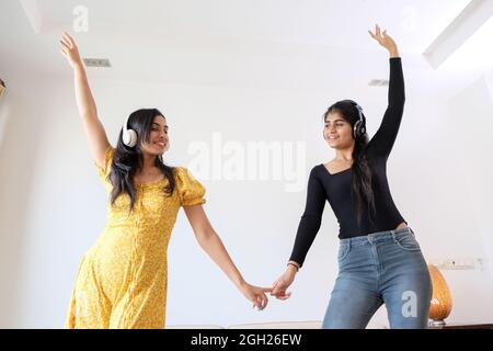 Young Indian girls with headphones having fun at home Stock Photo