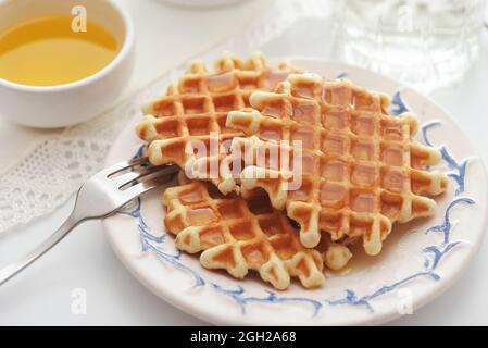 Freshly baked homemade belgian waffles with honey on white table Stock Photo