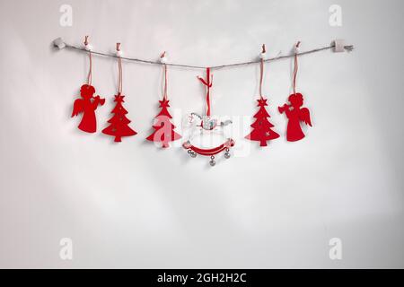 Christmas composition. A garland of red wooden toy fir trees and a rolling horse on a rough rope on a white background. Christmas, winter, new year co Stock Photo