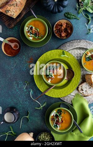 Top down vertical view of bowls of butternut squash soup surrounded by topping ingredients, ready for eating. Stock Photo