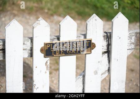 Please close gate sign on white wooden fence Stock Photo