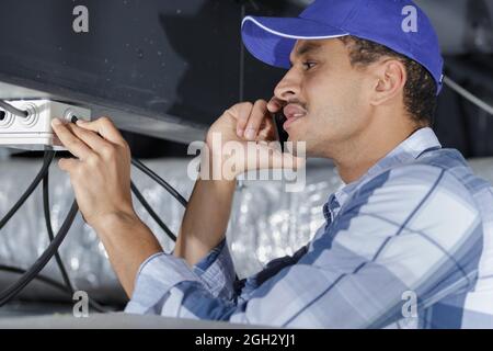 electrician sets the lamp on the ceiling Stock Photo