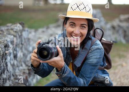 smiling female photographer crouching to take a picture Stock Photo