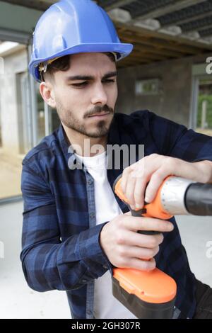young builder is drilling a wall Stock Photo