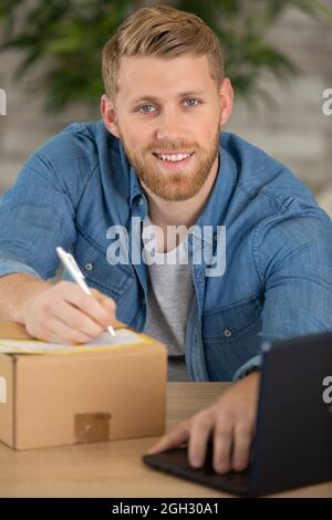 sme businessman writing address on parcel with labtop Stock Photo