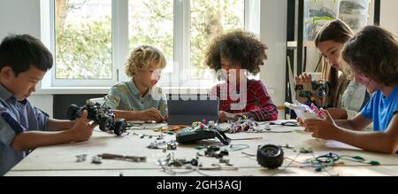 Multiracial school kids students making robotic cars using tablet computer. Stock Photo