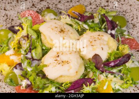 Warm salad with goat cheese and citrus fruits in composition Stock Photo