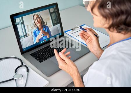 Female doctor consulting older senior patient during virtual video call visit. Stock Photo