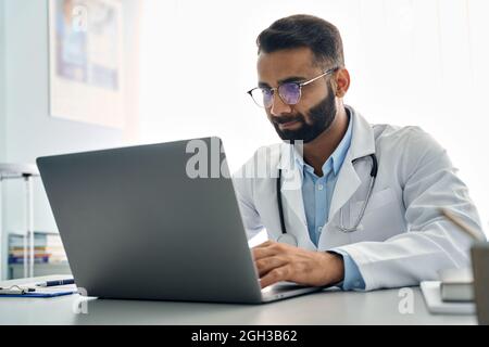 Indian male doctor using laptop computer at work in hospital. Stock Photo