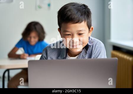 Happy Asian school boy using laptop computer at class in classroom. Stock Photo